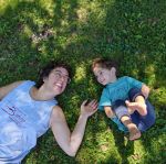 a mother laying on grass with her toddler