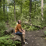 D'arcy sitting on a log in the forest, photo by Louana Meloche