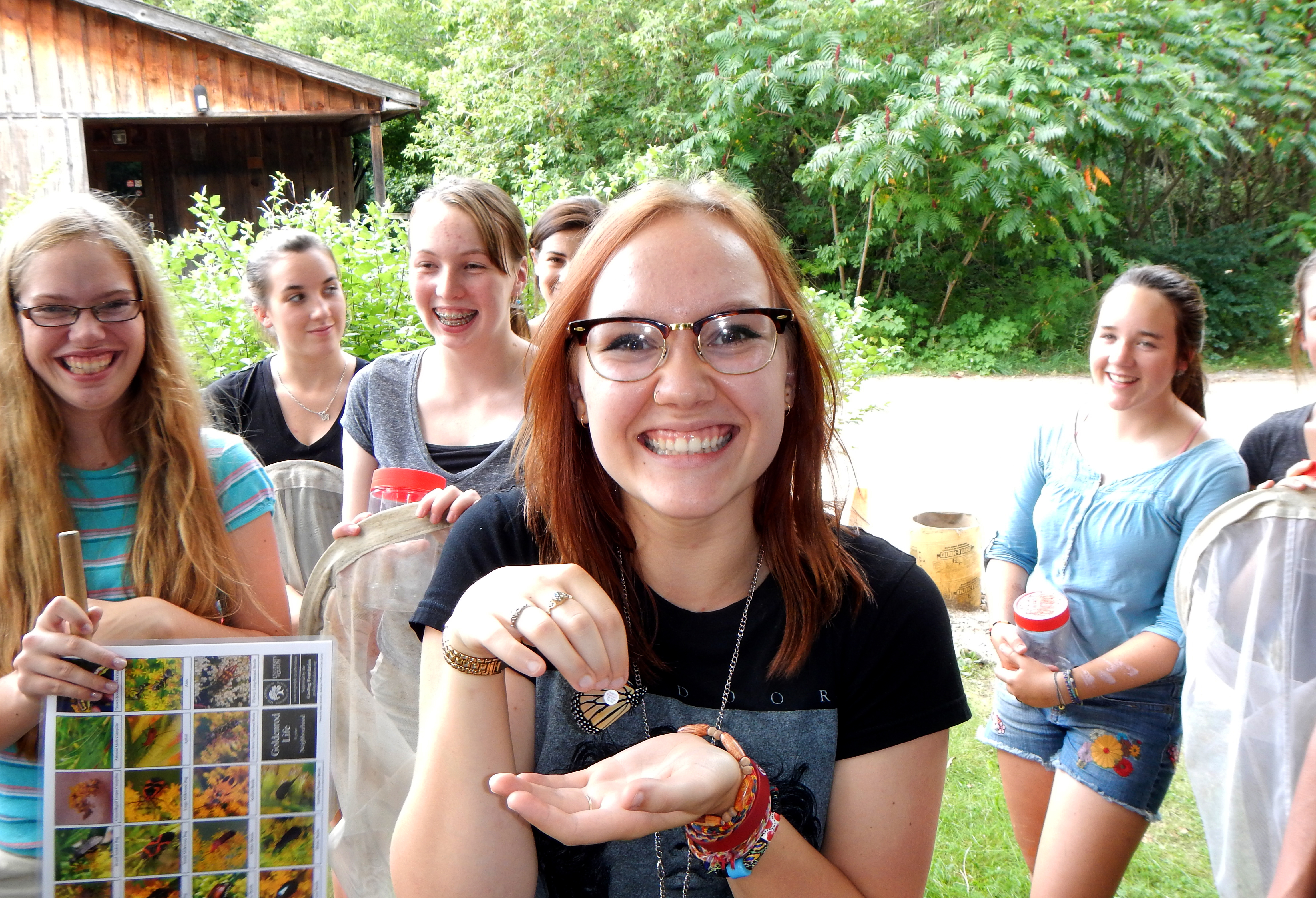 Person holding a tagged Monarch butterfly in front of the J.C. Taylor Nature Centre